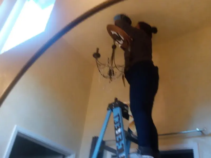 Electrician installing a chandelier in a University Heights residence